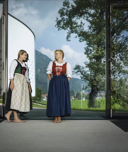 Frauen im Dirndl stehen vor Gläserner Tür