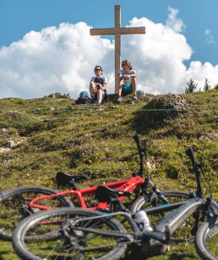 E-Bikes liegen auf Wiese Gipfelkreuz